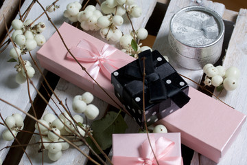 Wrapping presents. Gift boxes. Nearby there is a branch from a bush with autumn fruits of white color. Against the background of a wooden box.