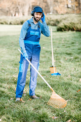 Professional male sweeper or gardener in uniform listening to the music with headphones while...