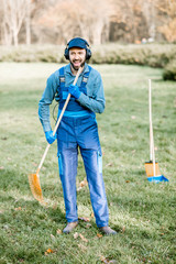 Professional male sweeper or gardener in uniform listening to the music with headphones while...