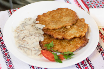 Potato pancakes with mushroom sauce on a white plate.