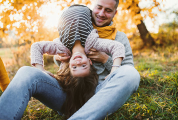 A young father having fun with a small daughter in autumn nature.