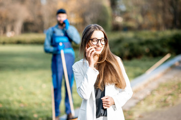 Elegant businesswoman walking through the man sweeping the street with arrogant attitude. Poverty...