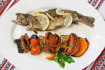 Grilled fish and grilled vegetables on a white plate.