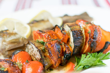 Grilled fish and grilled vegetables on a white plate.