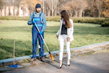Elegant businesswoman walking through the man sweeping the street with arrogant attitude. Poverty...