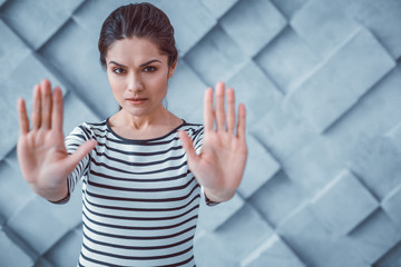 Act of protest. Dissent dark-haired woman pushing her hands forward showing disapprobation of...