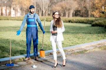 Businesswoman threw garbage with arrogant attitude near the man sweeping the street. Poverty and wealth concept