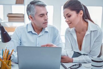 Obraz premium Working together. Tense workmates staying near the desk discussing and looking on each other