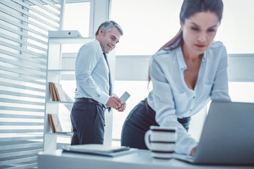 Beautiful woman working. Smiling handsome superior photographing charming fit employee while she fixing his computer