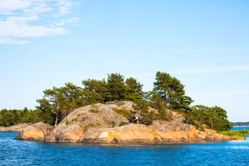 Rocky Island of Nicklösa in the Åland Islands, Finland, showing trees and orange crustose lichen.