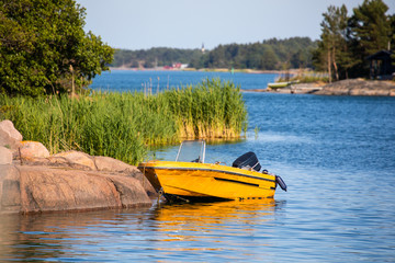 A moored motor boat along the rocky shore of the Island of Nicklösa in the Åland Islands, Finland, in the Baltic Sea.