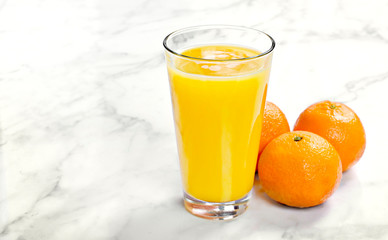 Fresh orange juice in a drinking glass, top view. Healthy fruit juice on white marble or stone background.