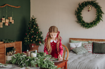 girl burgundy dress decorates Christmas rustic room