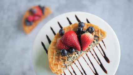 Waffles With Strawberry, Blue Berry and chocolate sauce in white plate.