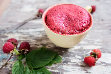 Raspberry muffin in mug and ripe raspberry berries on gray old wooden background