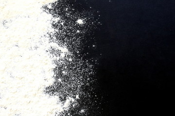White wheat flour scattered on a black background