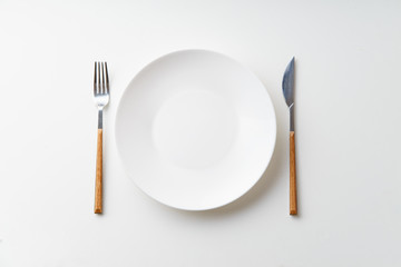 White empty plate with knife and fork on white background
