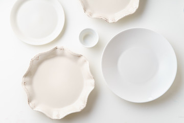 Porcelain plates of various form and size on white background. Overhead image, copy space.