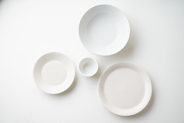 Porcelain plates of various form and size on white background. Overhead image, copy space.