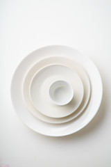 Porcelain plates of various form and size on white background. Overhead image, copy space.