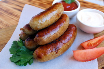 Pan-fried meat sausages with sauce and greens