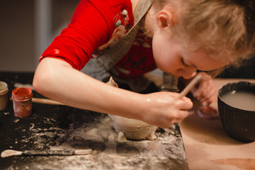 Young seven years old girl in pottery workshop creating a bowl from clay. Pottery workshop for kids