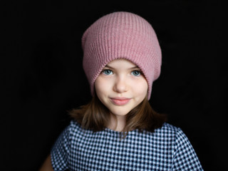 portrait of a cute preteen girl in a hat on a dark background
