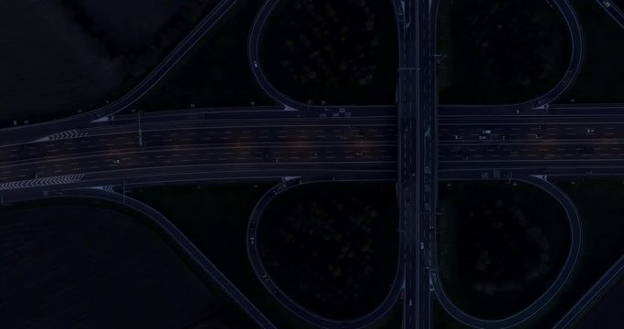 Night view of cloverleaf interchange seen from above. Aerial view of highway road junction in the night with evening traffic.
