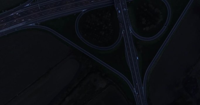 Night view of cloverleaf interchange seen from above. Aerial view of highway road junction in the night with evening traffic.