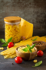 Various Pasta, Cheese, Spice and Tomatoes. Ingredients for cooking Pasta on a stone table. Copy space.