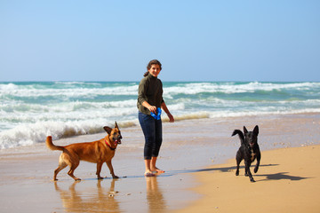 Teenage girl  playing with her dogs on the beach