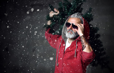 Fashionable modern Santa old man in red fashion hoodie and sunglasses Merry Christmas