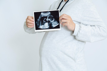 超音波エコーによる胎児の写真を見せる大きなお腹の妊婦。妊娠、胎児、健康、愛情、幸せイメージ