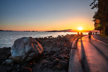People on the Seawall along English Bay in Vancouver at Sunset. Lens Flare. British Columbia, Canada.