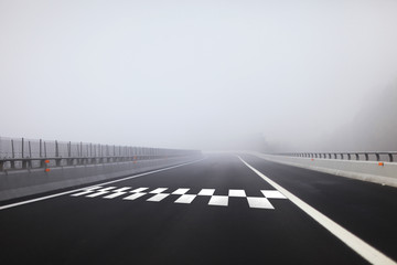 Start and Finish pattern line on the heavy foggy highway. - obrazy, fototapety, plakaty