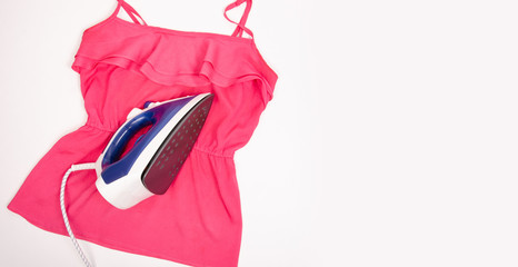 Blue iron and pink shirt on ironing board top view, household. Isolation white background