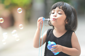 Asian little cute girl or kid blow,play air soap bubbles with smile. happiness,fun and childhood...
