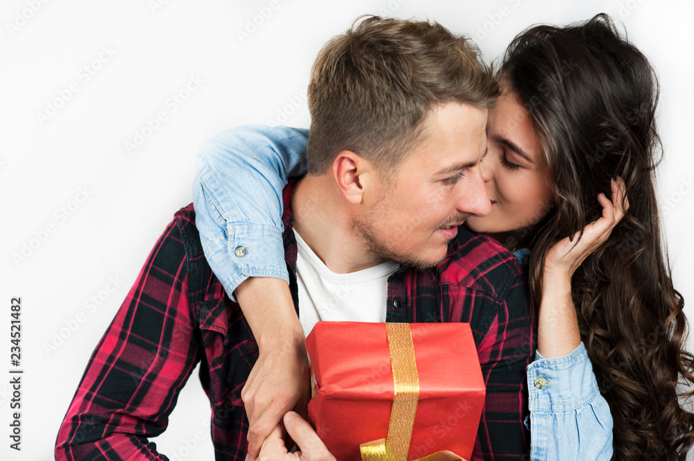 Wall mural young couple in love guy and girl give each other a gift and react emotionally looking at the box