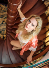 girl in silk robe stand on wooden spiral staircase
