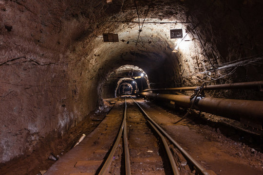 Underground gold iron ore mine shaft tunnel gallery passage with light and rails