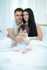 Happy couple and son sitting in bed
