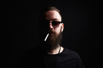 handsome Brutal bearded smoking man in sunglasses