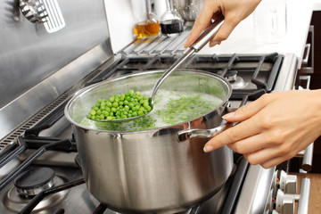 WOMAN IN KITCHEN COOKING PEAS