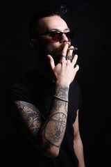 Brutal bearded smoking man in sunglasses