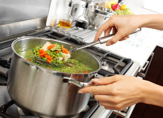 WOMAN IN KITCHEN COOKING MIXED VEGETABLES