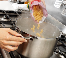 WOMAN IN KITCHEN COOKING PASTA