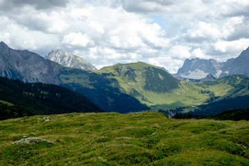 Almwiesen mit Alpengipfeln und Wolken