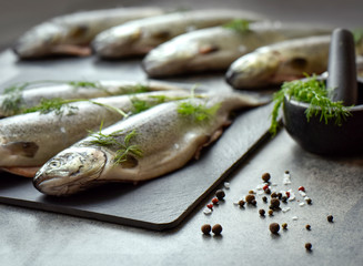 Rainbow trouts on a stone board with herbs