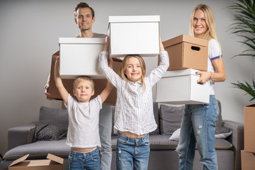 Fototapeta na wymiar Full-length image of young married couple with children with cardboard boxes in their hands standing
