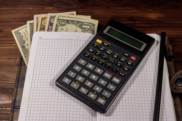 Notepad with dollars, pencil and calculator on wooden desk. Financial planning concept